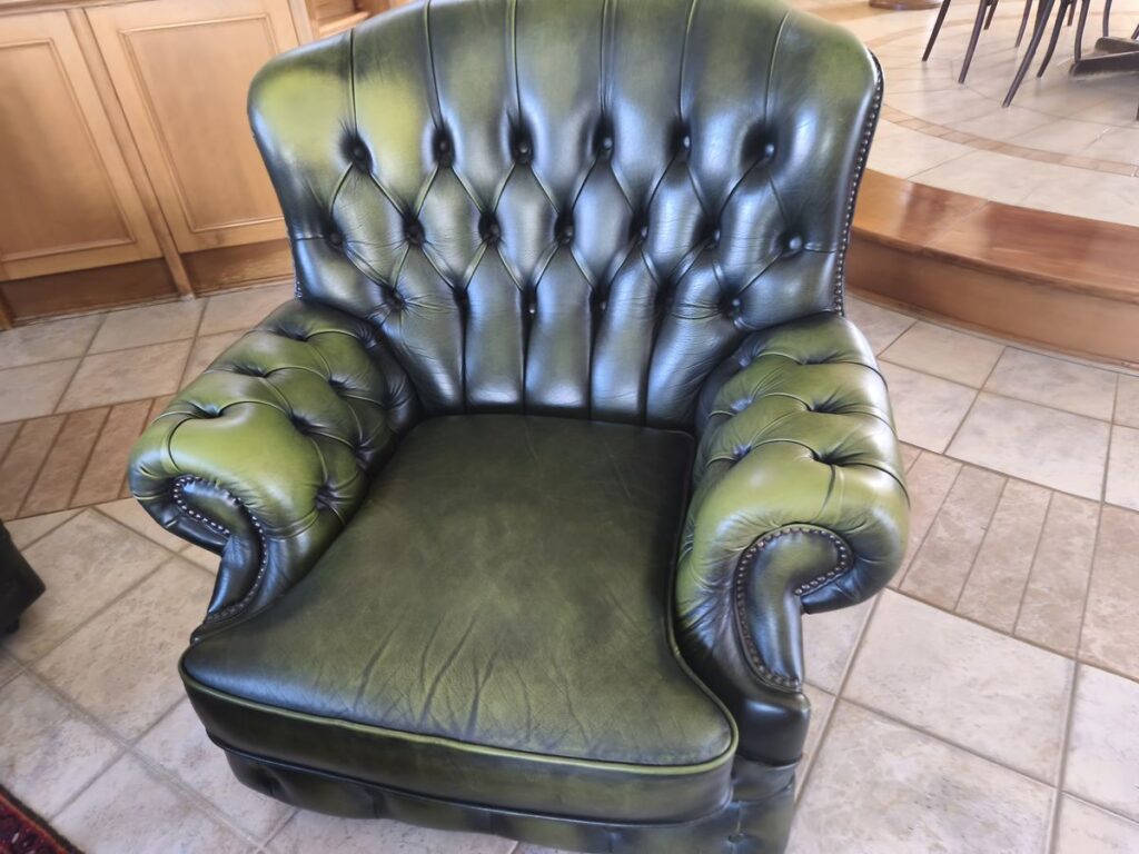 Zöld Chesterfield fotel kárpitozás előtt, megereszkedett ülőpárnával
